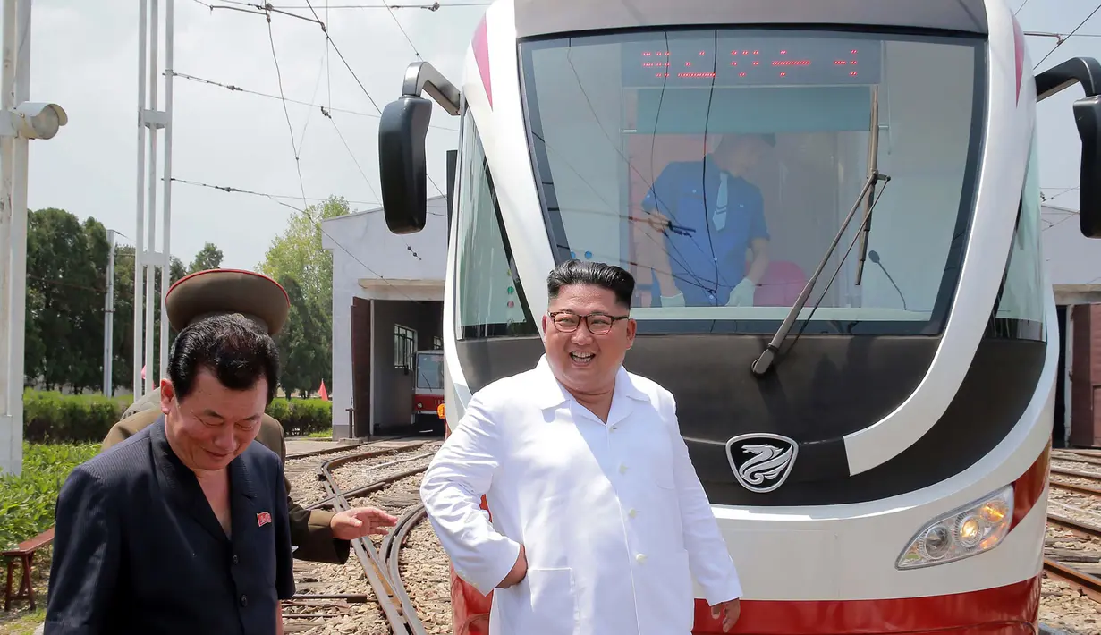 Pemimpin Korea Utara Kim Jong-Un tersenyum saat melihat kereta ringan selama kunjungan ke pabrik bus di Pyongyang, (4/8). Tak hanya bus, pabrik tersebut juga membuat kereta ringan atau trem. (AFP Photo/KCNA)