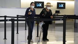 Pelancong memakai masker di loket tiket di Bandara Internasional Los Angeles, Senin (25/4/2022). Seminggu sebelumnya, seorang hakim federal di Florida menolak persyaratan untuk memakai masker di bandara dan selama penerbangan. Aturan itu, yang dirancang untuk membatasi penyebaran COVID-19, akan berakhir pada 3 Mei. (AP Photo/Marcio Jose Sanchez)