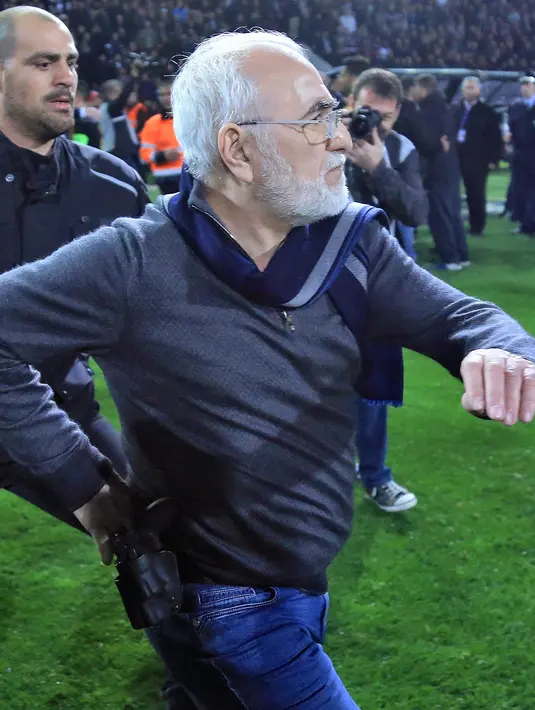 Presiden PAOK Ivan Savvidis turun ke lapangan dengan pistol di pinggangnya saat Liga Super Yunani di Stadion Toumbas, Minggu (11/3). Savvidis memprotes wasit yang membatalkan gol PAOK yang dicetak Fernando Valera pada menit ke-89. (InTime Sports via AP)