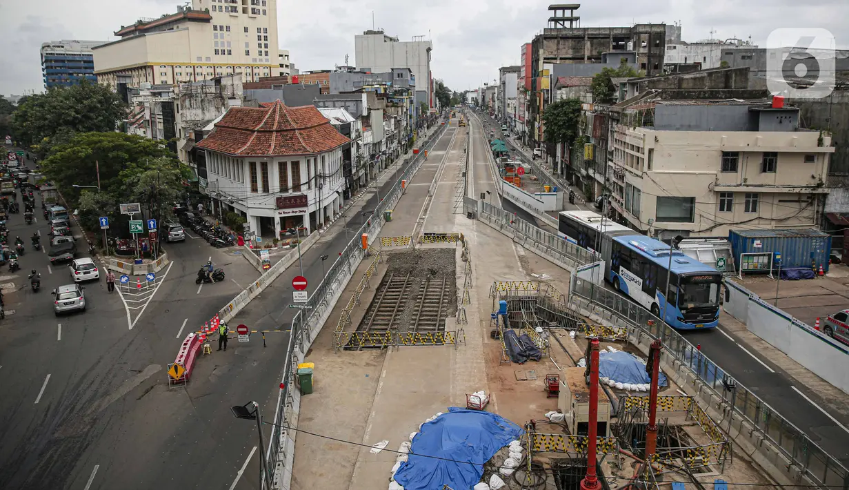 Transjakarta melintas dekat lokasi ditemukannya rel trem di lokasi pembangunan MRT Jakarta fase 2, Glodok, Jakarta, Selasa (28/12/2021). Rel trem itu ditemukan di bawah jalur TransJakarta di Jalan Pintu Besar Selatan pada Desember 2021. (Liputan6.com/Faizal Fanani)