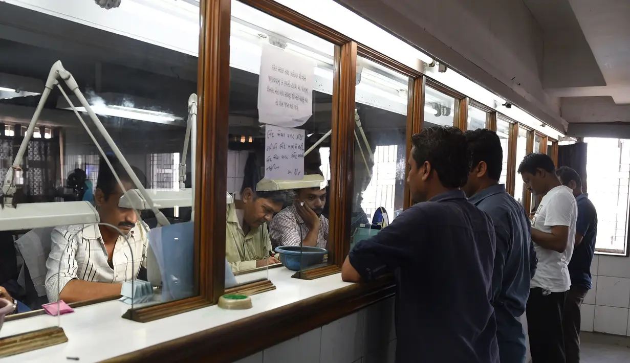 Para pekerja menunggu untuk menyerahkan berlian yang akan dipoles di bengkel pemotongan dan pemolesan berlian di Ahmedabad (23/7/2019). India merupakan pusat pemotongan dan pemolesan berlian terbesar di dunia. (AFP Photo/Sam Panthaky)