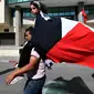 Orang-orang melambaikan bendera Palestina selama protes untuk mengekspresikan solidaritas mereka terhadap Gaza di ibu kota Tunisia, Tunis, pada 21 Oktober 2023, di tengah pertempuran yang sedang berlangsung antara Israel dan kelompok Palestina Hamas. (FETHI BELAID / AFP)