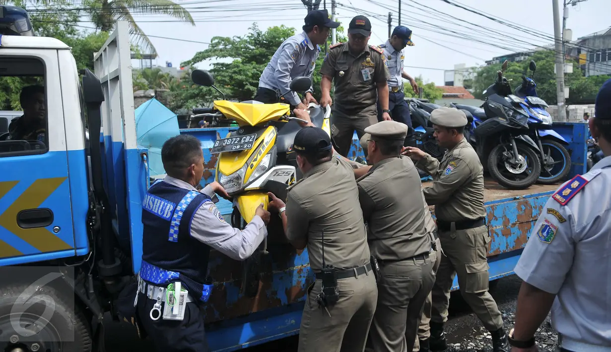 Petugas Dishub DKI dibantu Satpol PP mengangkut motor yang parkir di bahu jalan kawasan Kebayoran Lama, Jakarta, Kamis (12/5). Razia dilakukan untuk membuat jera pengendara yang memarkir kendaraan bukan pada tempatnya (Liputan6.com/Gempur M Surya)