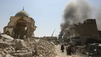 Warga sipil Irak melewati Masjid Agung al-Nuri yang hancur saat mengungsi dari Kota Tua di Mosul, 30 Juni 2017. Masjid yang dibangun pada abad ke-12 ini diledakkan ISIS pada 21 Juni 2017 sebagai upaya menghambat laju pasukan Irak. (AHMAD AL-RUBAYE/AFP)