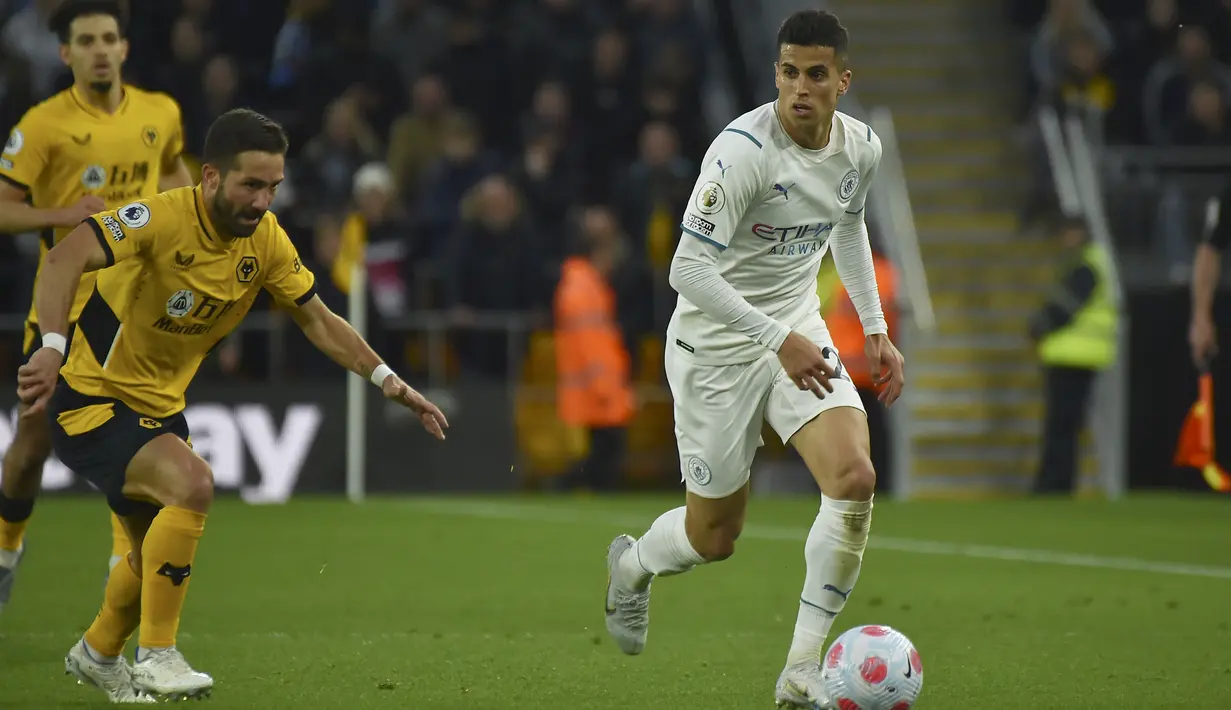 <p>Bek Manchester City Joao Cancelo berlari dengan bola menjauhi gelandang Wolverhampton WanderersJoao Moutinho pada laga tunda pekan ke-33 Liga Inggris di Molineux Stadium, Kamis (12/5/2022). Kevin De Bruyne mencatatkan empat gol yang menakjubkan saat Manchester City melibas 5-1 tuan rumah Wolverhampton Wanderers. (AP Photo/Rui Vieira)</p>