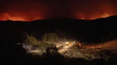 Alat berat dikerahkan untuk membuat sekat saat kebakaran hutan yang disebut Highland Fire membakar di Aguanga, California, Senin, 30 Oktober 2023. (AP Photo/Ethan Swope)