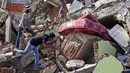 Warga memeriksa bangunan yang runtuh akibat gempa di Mamuju, Sulawesi Barat, Indonesia, Senin (18/1/2021). Hingga Minggu 17 Januari 2021 pukul 20.00 WIB, BNPB melaporkan jumlah korban meninggal akibat gempa Sulawesi Barat menjadi 81 orang. (AP Photo/Yusuf Wahil)