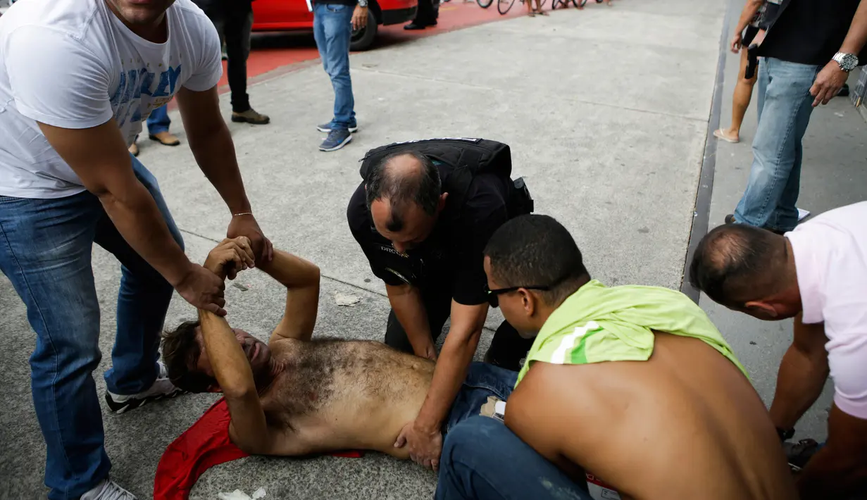 Polisi sipil menahan penjarah setelah mereka ditembak di kakinya di Vitoria, negara bagian Espirito Santo, Brasil, (7/2). Kejahatan Espirito Santo meningkat setelah polisi mogok kerja. (AP Photo / Diego Herculano)