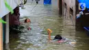 Sejumlah anak bermain banjir yang merendam kawasan Kampung Melayu Kecil, Bukit Duri, Jakarta, Selasa (25/2/2020). Banjir tersebut akibat luapan sungai Ciliwung. (merdeka.com/magang/ Muhammad Fayyadh)