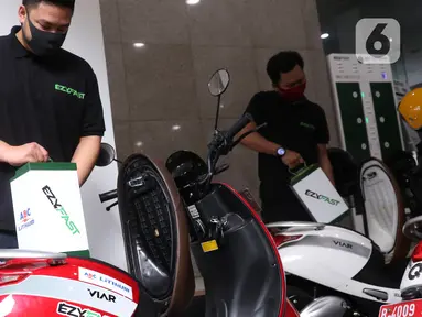 Petugas menguji coba penukaran baterai sepeda motor listrik di halaman kantor Ditjen Ketenagalistrikan ESDM, Jakarta, Senin (31/8/2020). Stasiun Penukaran Baterai Kendaraan Listrik Umum (SPBKLU) ini diharap dapat meningkatkan permintaan listrik dari energi baru terbarukan (Liputan6.com/Angga Yuniar)