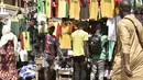 Seorang pria berjalan melewati kios yang menjual kaus tim sepak bola Senegal di Dakar (4/2/2022). Senegal akan bertanding melawan Mesir pada babak final Piala Afrika 2021 di Paul Biya stadium, Senin (7/2/2022) dini hari WIB besok. (AFP/Seyllou)