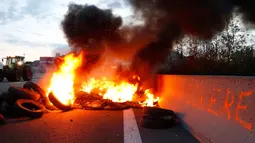 Para petani Perancis memblokir salah satu ruas jalan utama di Seclin, Perancis, Rabu (22/7/2015). Tampak, asap hitam membumbung tinggi saat puluhan ban dibakar para petani saat melakukan aksi di ruas jalan utama di Seclin. (REUTERS/Pascal Rossignol)