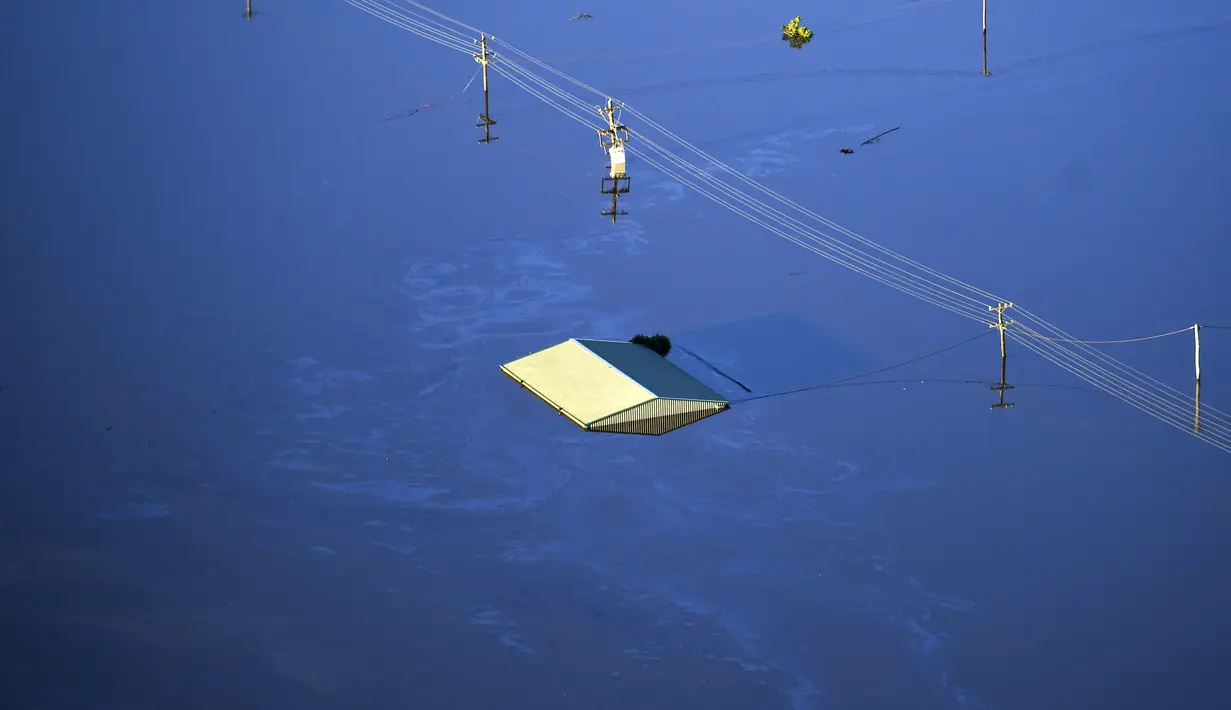Atap bangunan terlihat terendam air banjir yang menutupi area yang luas di barat laut Sydney, Australia, Rabu  (24/3/2021).  Sekitar 18.000 penduduk negara bagian terpadat di Australia telah meninggalkan rumah mereka sejak pekan lalu, dengan peringatan banjir dapat berlanjut hingga April. (Lukas Coc