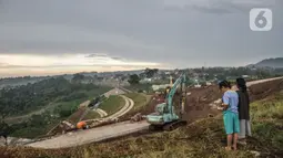 Anak-anak saat melihat aktivitas proyek pembangunan Bendungan Ciawi, Bogor, Jawa Barat, Minggu (18/12/2022). Bendungan kering pertama di Indonesia itu akan digunakan untuk pengendalian banjir di wilayah Jakarta ketika musim hujan, karena mampu mereduksi debit air yang mengalir dari Sungai Ciliwung. (merdeka.com/Iqbal S. Nugroho)