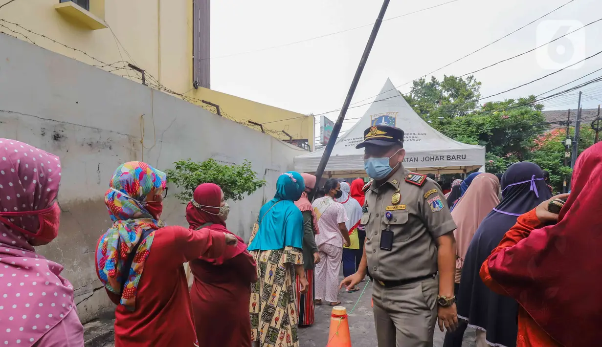 Petugas mengatur antrean warga yang membeli minyak goreng murah di depan Kantor Kecamatan Johar Baru, Jakarta, Senin (17/1/2022). Sudin PPKUKM Jakarta Pusat menggelar operasi pasar (OP) minyak goreng murah dengan harga Rp 14.000 per liter. (Liputan6.com/Herman Zakahria)