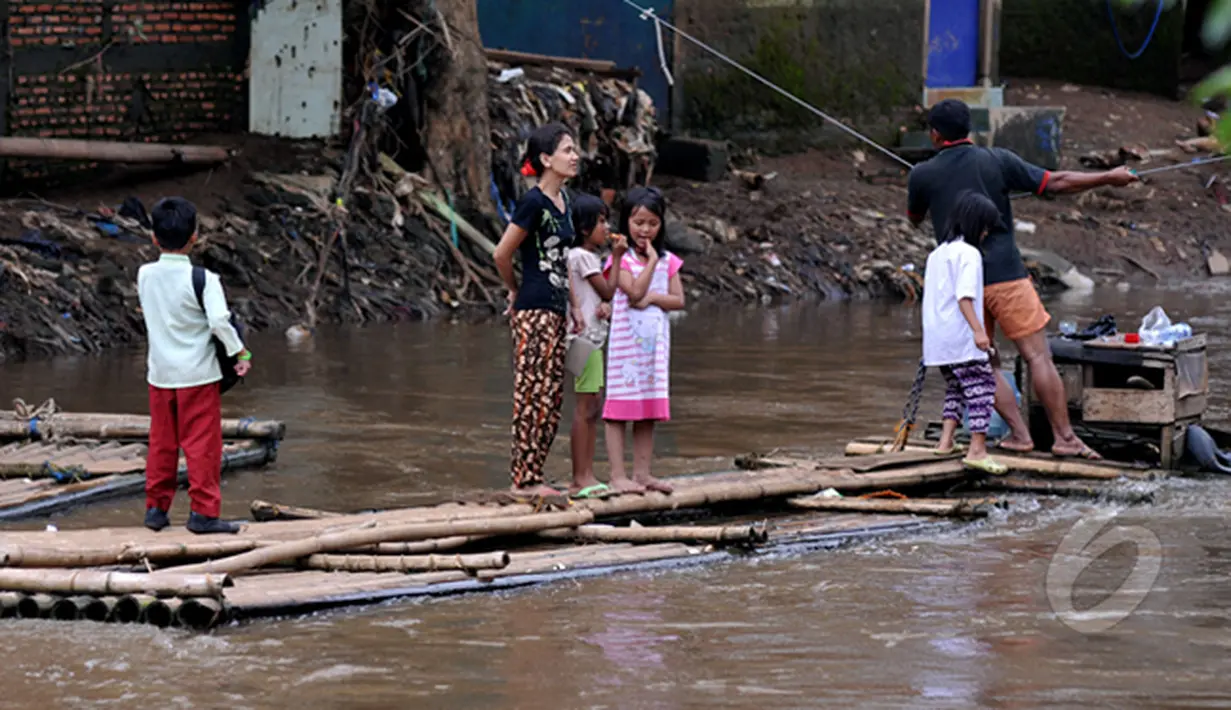 Masih banyak warga bantaran kali Ciliwung Jakarta yang memanfaatkan air kali untuk kehidupan sehari - hari. Tampak aktivitas warga saat menyebrangi kali Ciliwung, Jakarta, Jumat (20/2/2015). (Liputan6.com/JohanTallo)