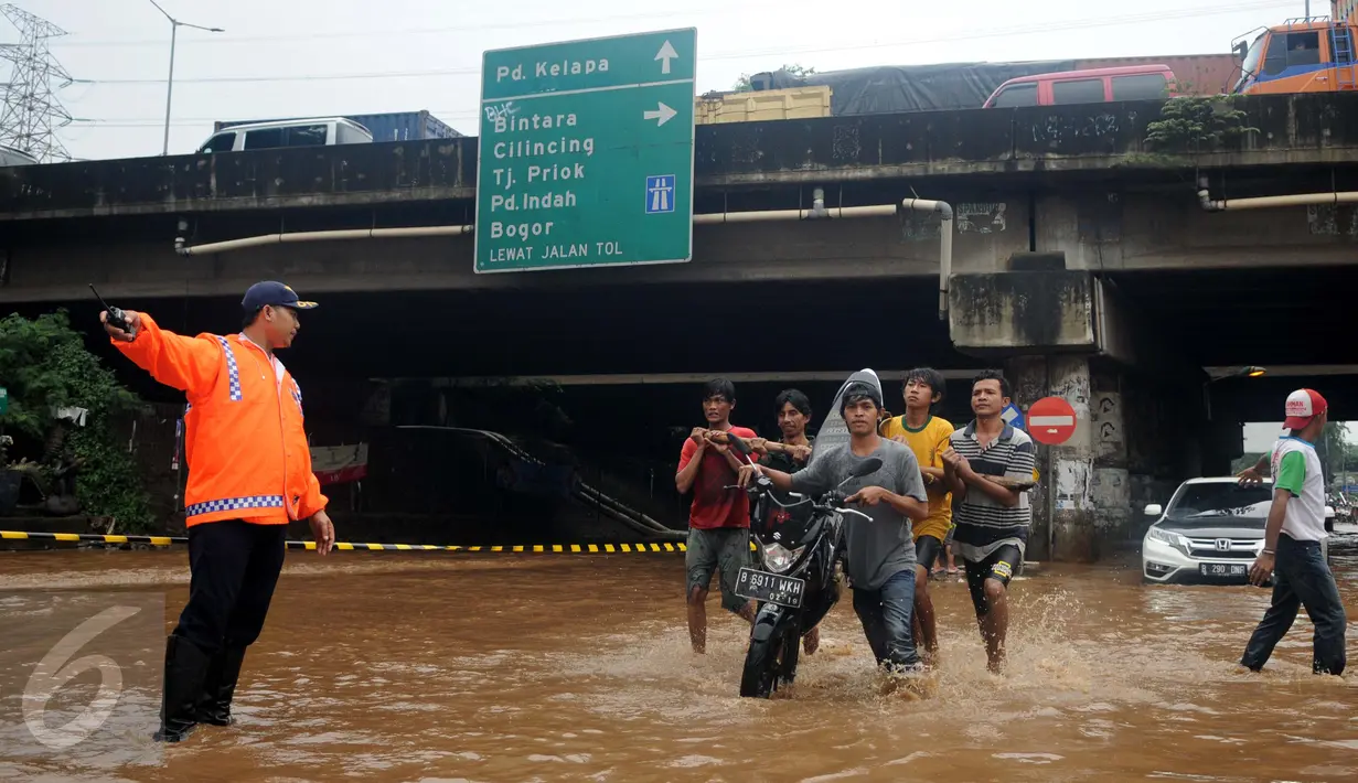 Warga membantu mendorong motor yang mogok saat berusaha menerobos banjir di Jalan Raya Kalimalang, Caman, Bekasi, Senin (20/2). Imbas banjir, ruas Jalan Kalimalang dari arah Jakarta menuju Bekasi dan sebaliknya ditutup (Liputan6.com/Gempur M Surya)
