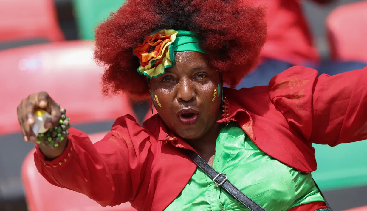 Seorang Suporter Kamerun bersorak menjelang upacara pembukaan turnamen Piala Afrika (CAN) 2021 di Stade d'Olembé di Yaounde (9/1/2022). Piala Afrika 2021 seharusnya digelar Januari 2021 tapi kemudian diundur karena pandemi. (AFP/Kenzo Tribouillard)