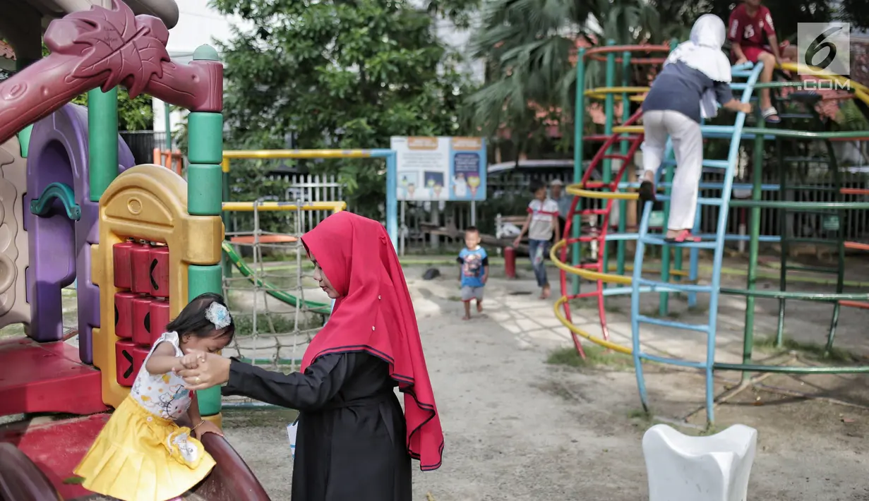 Seorang anak didampingi orangtuanya bermain di RPTRA Taman Kenanga, Jakarta, Selasa (28/9). Pemerintah Provinsi DKI Jakarta menargetkan pada tahun ini akan membangun 16 Ruang Publik Terpadu Ramah Anak (RPTRA). (Liputan6.com/Faizal Fanani)