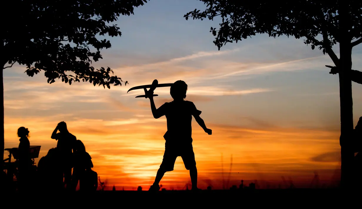 Seorang anak laki-laki bermain dengan pesawat mainan saat matahari terbenam di bukit Kronberg di Hannover, Jerman utara (6/8). (AP Photo/Julian Stratenschulte)