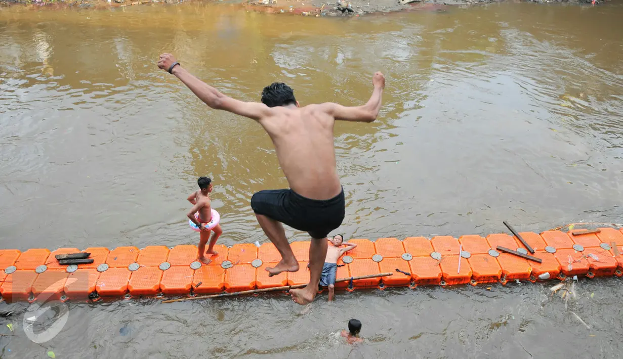 Seorang anak bantaran Sungai Ciliwung melompat ke sungai dari atas jembatan Manggarai, Jakarta, Rabu (18/5/2016). Kondisi air Sungai Ciliwung tidak lagi dipenuhi sampah dan lebih jernih. (Liputan6.com/Yoppy Renato)