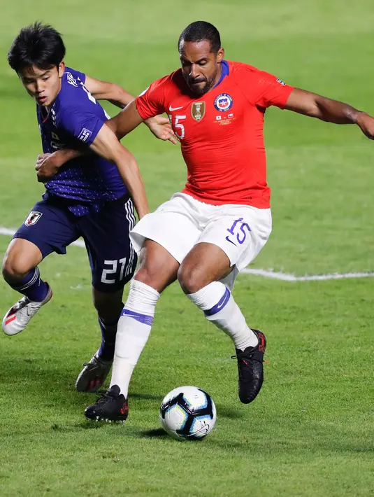 Gelandang Jepang, Takefusa Kubo (kiri) berusaha merebut bola yang dibawa pemain Chile, Jean Beausejour selama pertandingan grup C Copa America 2019 di Stadion Morumbi, Sao Paulo, Brasil (17/6/2019). Kubo resmi dikontrak selama enam tahun oleh Real Madrid. (AFP Photo/Nelson Almeida)