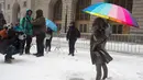 Warga mengambil gambar patung Fearless Girl memakai payung di New York, AS (14/3).  Badai salju menerjang kawasan Amerika Serikat timur laut, dari West Virginia hingga Maine, menyebabkan hujan salju lebat di sejumlah tempat. (AFP Photo/Don Emmert)