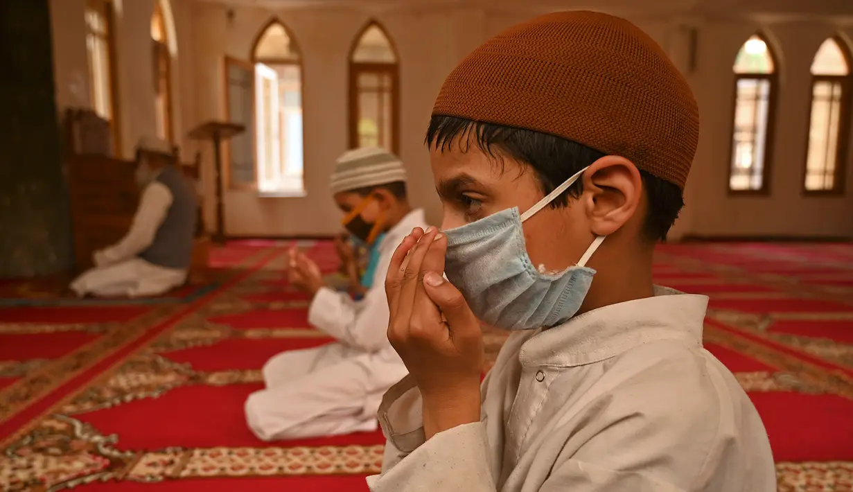 Anak-anak yatim Muslim mengenakan masker berdoa sambil menjaga jarak sosial di dalam pusat panti asuhan selama bulan suci Ramadan di Srinagar (11/5/2020). (AFP/Tauseff Mustafa)