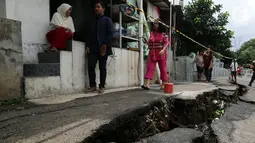 Warga beraktivitas di dekat jalan yang retak di Kelurahan Kebon Manggis, Kecamatan Matraman, Jakarta Timur, Jumat (16/2). Kendaraan yang ingin melintasi jalan tersebut dialihkan ke jalan-jalan lain di sekitarnya. (Liputan6.com/Johan Tallo)
