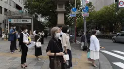 Orang-orang yang memakai masker wajah untuk membantu mengekang penyebaran virus korona menunggu untuk menyeberang persimpangan di Tokyo (28/5/2021). Infeksi virus corona di Jepang masih belum melambat saat bersiap untuk menjadi tuan rumah Olimpiade hanya dalam waktu 50 hari. (AP Photo/Hiro Komae)