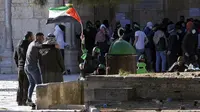 Seorang pengunjuk rasa Palestina mengibarkan bendera Palestina saat bentrokan dengan pasukan keamanan Israel di Kompleks Masjid Al Aqsa, Kota Tua Yerusalem, 15 April 2022. (AP Photo/Mahmoud Illean)