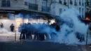 Petugas polisi berdiri di tengah asap gas air mata saat mereka bentrok dengan anggota komunitas Kurdi dekat TKP tempat terjadinya penembakan di Paris, Prancis, 23 Desember 2022. Polisi sampai harus mengeluarkan gas air mata untuk meredam aksi massa. (AP Photo/Lewis Joly)