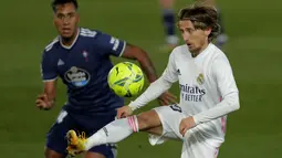 Gelandang Real Madrid, Luka Modric (kanan) mengontrol bola dari kawalan pemain Celta Vigo, Renato Tapia pada pertandingan lanjutan La Liga Spanyol di stadion Alfredo Di Stefano, Minggu (3/1/2021). Skuad asuhan Zidane ke puncak klasemen sementara dengan 36 poin dari 17 laga. (AP Photo/Manu Fernandez)