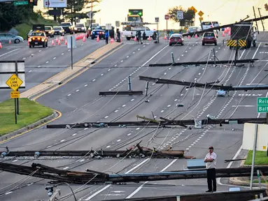 Pemandangan arah timur dari Route 97, seorang pria berdiri melihat tiang listrik yang tumbang di Route 140, Westminster, Maryland, Amerika Serikat, Selasa (8/8/2023). Tiang listrik bertumbangan setelah badai dahsyat melanda area tersebut pada Senin malam. (Jerry Jackson/The Baltimore Sun via AP)