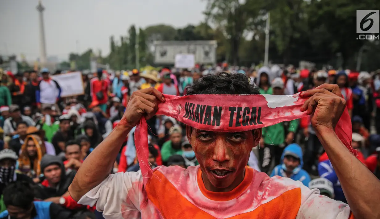 Seorang massa dari Aliansi Nelayan Indonesia memasang ikat kepala saat berunjuk rasa di depan Istana Merdeka, Jakarta, Selasa (11/7). Dalam aksi itu, mereka menyampaikan tuntutannya terkait kebijakan Menteri Susi Pudjiastuti. (Liputan6.com/Faizal Fanani)