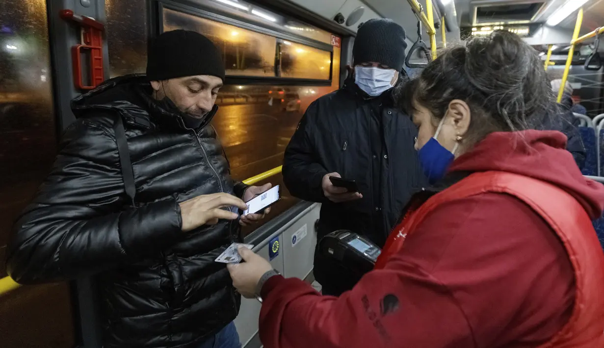 Seorang petugas memeriksa kode QR penumpang yang membuktikan tidak adanya infeksi virus corona pada layar ponsel pintar, di dalam bus di Kazan, Senin (22/11/2021). Kazan, menjadi yang pertama di Rusia yang mulai mewajibkan bukti vaksinasi sebelumnya untuk akses transportasi umum. (AP Photo)