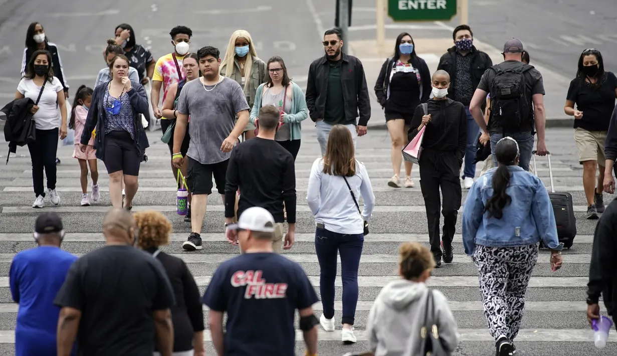 <p>Pejalan kaki dengan masker dan tanpa masker berjalan di sepanjang Las Vegas Strip, di Las Vegas Selasa (27/4/2021). Warga Amerika Serikat (AS) yang telah menerima vaksin COVID-19 tidak lagi diwajibkan mengenakan masker saat berada di luar ruangan jika tidak ada kerumuman. (AP Photo/John Locher)</p>