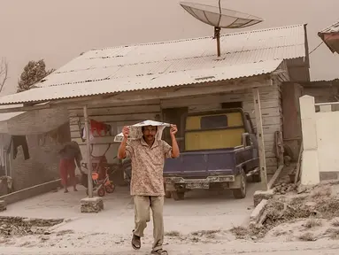 Warga menutupi kepalanya untuk menghindari abu vulkanik akibat erupsi Gunung Sinabung yang menghujani Desa Tiga Pancur, Karo, Sumatera Utara, Rabu (2/8). Sinabung meluncurkan awan panas hingga 20 kali sepanjang hari ini disertai erupsi. (IVAN DAMANIK/AFP)