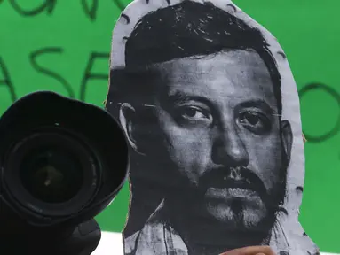 Seorang  memegang kamera dan foto Ruben Espinosa Ruben saat menggelar protes di monumen Kemerdekaan di Mexico City, Meksiko, Minggu (2/8/2015).   Ruben Espinosa adalah seorang wartawan investigasi untuk majalah Proceso. (REUTERS/Henry Romero)