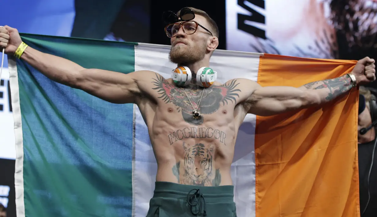 Conor McGregor membentangkan bendera Irlandia saat timbang badan jelang melawan Floyd Mayweather di Las Vegas (25/8/2017). McGregor akan bertarung 26 agustus 2017. (AP/John Locher)