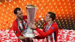 Pemain Atletico Madrid Diego Godin (kiri) dan rekannya Antoine Griezmann mengangkat piala saat merayakan kemenangannya usai menjadi juara Liga Europa 2018 di Stade de Lyon, Prancis (16/5). (AP Photo / Christophe Ena)