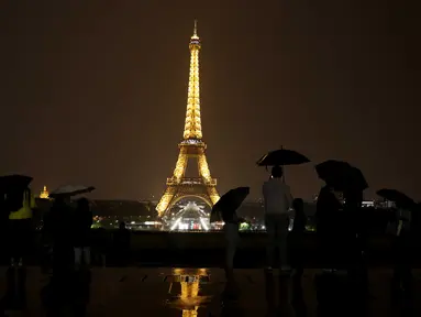 Sejumlah wisatawan menikmati pemandangan Menara Eiffel yang diterangi lampu dari Trocadero Plaza di Paris, Prancis (1/9).( AFP Photo/Ludovic Marin)