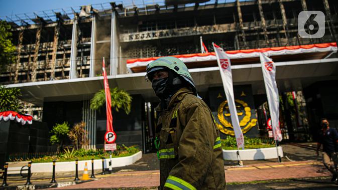 Petugas pemadam kebakaran melintas di depan gedung utama Kejaksaan Agung yang terbakar di Jakarta, Minggu (23/8/2020). Pemadaman kebakaran di gedung Kejaksaan Agung kini sudah memasuki tahap pendinginan, pascapemadaman dilakukan hingga lebih dari 11 jam. (Liputan6.com/Faizal Fanani)