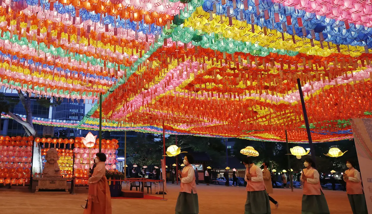 Umat Buddha mengenakan masker membawa lampion untuk merayakan ulang tahun Buddha yang akan datang pada 19 Mei di kuil Jogye, Seoul, Korea Selatan (6/5/2021). Warna-warni lampion dipasanga untuk merayakan ulang tahun Buddha yang akan datang pada 19 Mei. (AP Photo/Lee Jin-man)