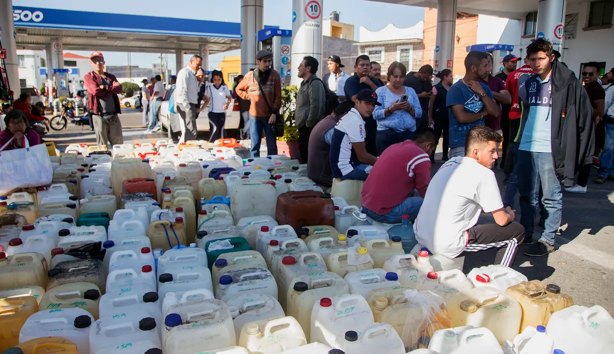 Warga antre menggunakan jerigen di tengah kelangkaan BBM di sebuah SPBU di Morelia, Meksiko, Selasa (8/1). Antrean disebabkan pasokan BBM ke beberapa negara bagian di Meksiko mengalami kekurangan akibat kasus pencurian bahan bakar. (ENRIQUE CASTRO/AFP)