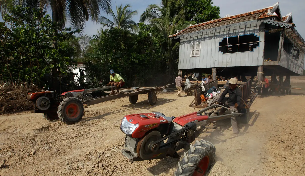 Warga menggunakan traktor untuk memindahkan rumah di Desa Serey Andet di provinsi Kampong Speu, Kamboja (27/3). Mereka memindahkan rumah dengan cara tersebut dengan tujuan agar rumah tetap utuh. (AP Photo/Heng Sinith)