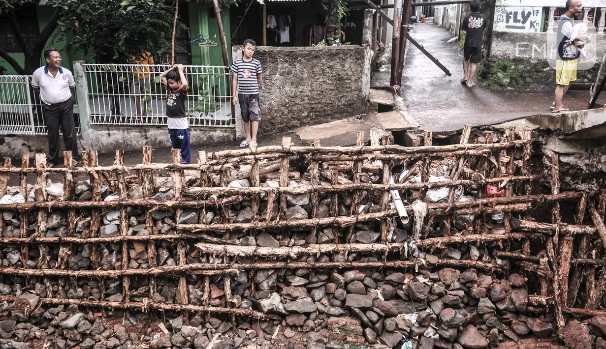 Warga mengamati turap kali yang longsor di Batu Ampar, Kramat Jati, Jakarta, Selasa (23/2/2021). Turap kali sepanjang 30 meter di permukiman RT 17 dan 13 RW 02 Kelurahan Batu Ampar longsor pada Sabtu (20/2) akibat derasnya arus air ketika aliran Kali Ciliwung meluap. (merdeka.com/Iqbal S. Nugroho)
