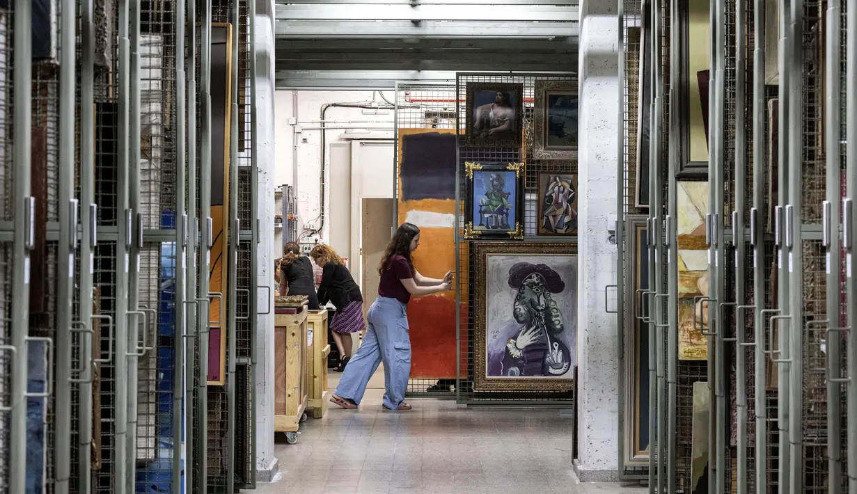 Nathalie Andrijasevic (kanan), asisten kurator di Museum Seni Tel Aviv, menangani lukisan-lukisan yang dipindahkan ke ruang aman bawah tanah karena konflik yang sedang berlangsung antara Israel dan Hamas serta ketegangan regional yang sedang berlangsung dengan Iran dan Hizbullah, di museum, di Tel Aviv, 13 Agustus 2024. (Oren ZIV / AFP)