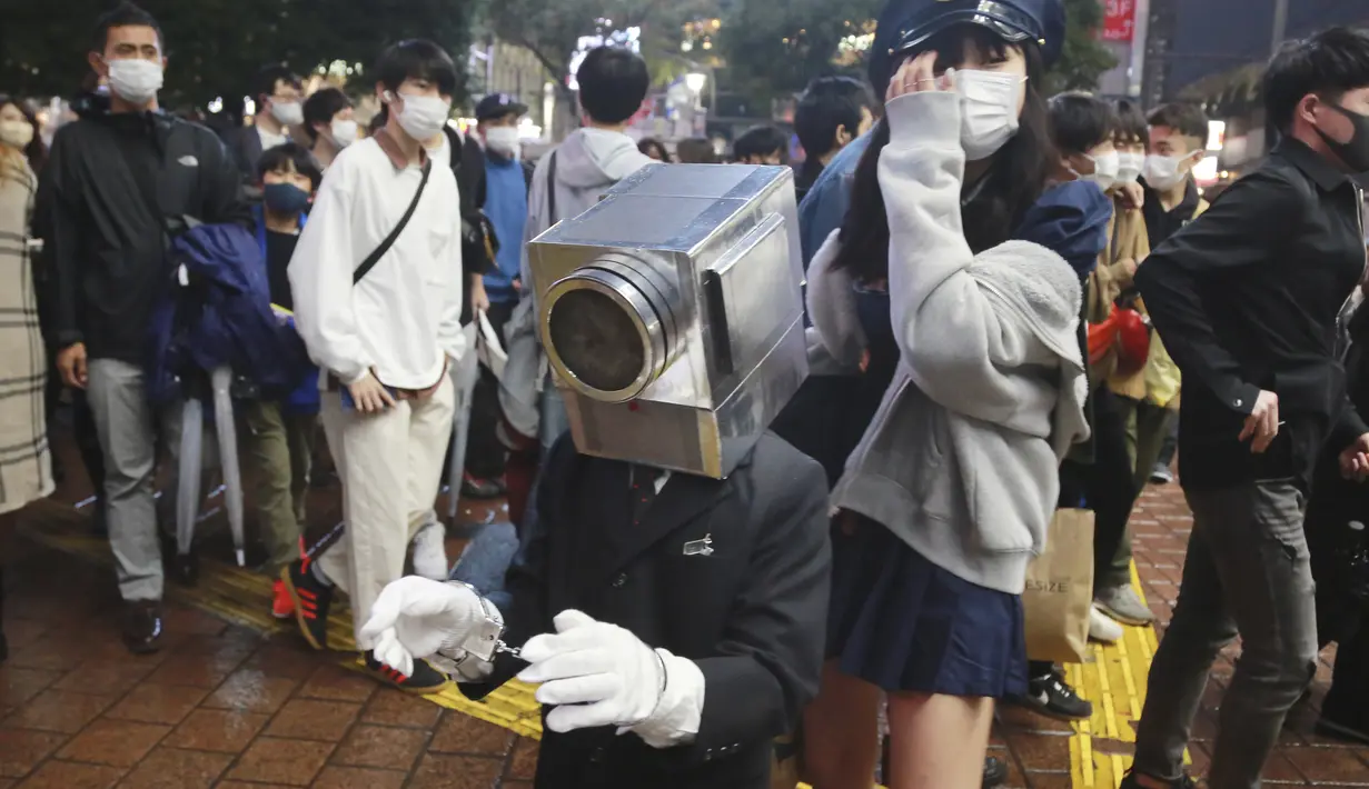 Orang-orang yang mengenakan kostum Halloween yang kreatif berjalan melalui distrik Shibuya yang populer di Tokyo, Minggu (31/10/2021). Daerah di sekitar Stasiun Shibuya dipadati anak-anak muda yang berdandan selama Halloween setiap tahun. (AP Photo/Koji Sasahara)