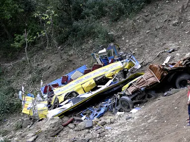 Warga berkerumun untuk melihat bangkai bus sekolah yang rusak akibat masuk jurang di dekat Nurpur, Distrik Kangra, Himachal Pradesh, India, Selasa (10/4). Setidaknya 30 orang tewas, termasuk 27 anak-anak. (SHAMMI MEHRA/AFP)